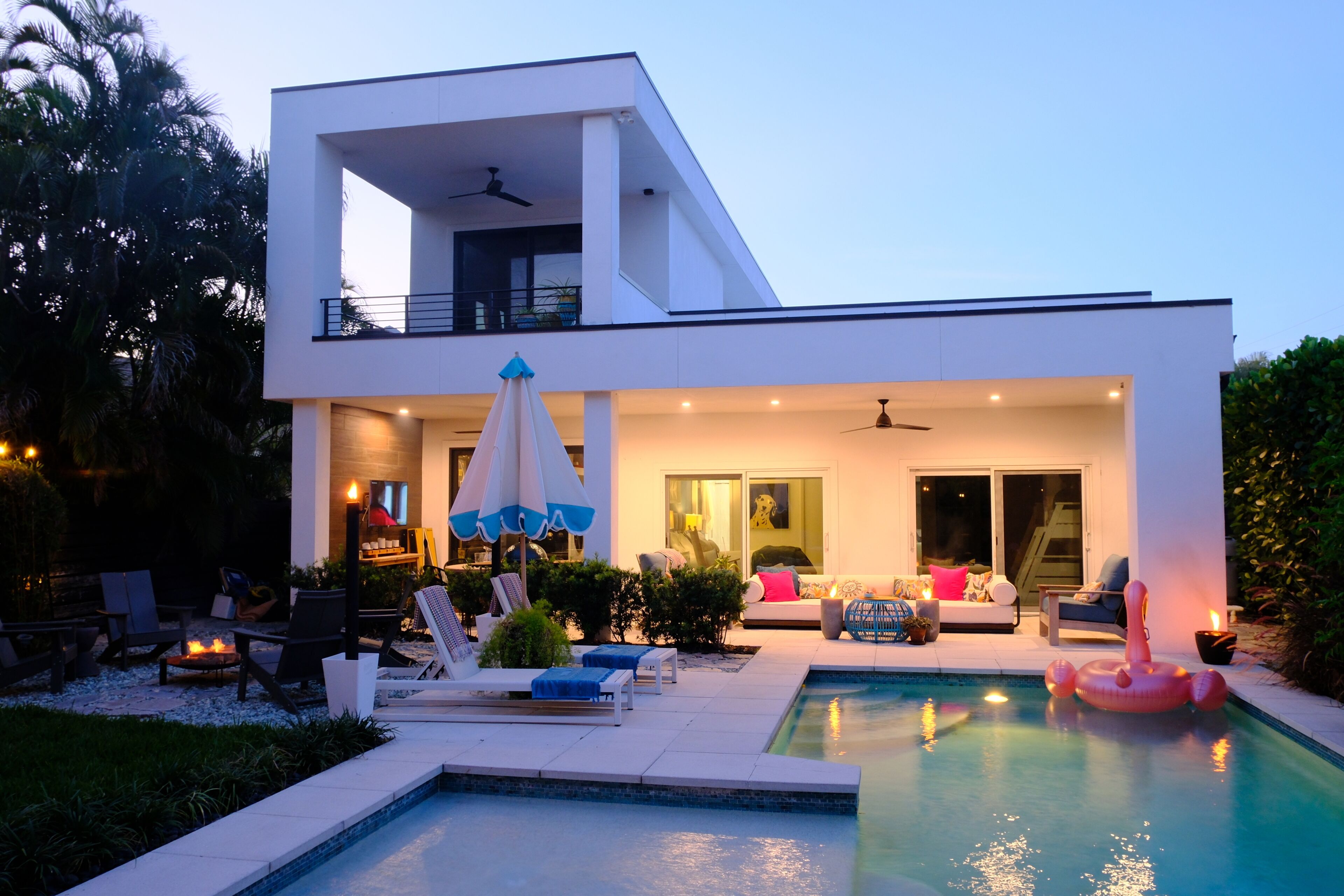 A modern two-story house with a swimming pool, outdoor seating, and a balcony.