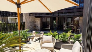 A rooftop patio with outdoor seating, a large umbrella, and a view of the building's interior.