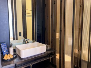 Un bagno con lavandino bianco, uno specchio e un portasciugamani.