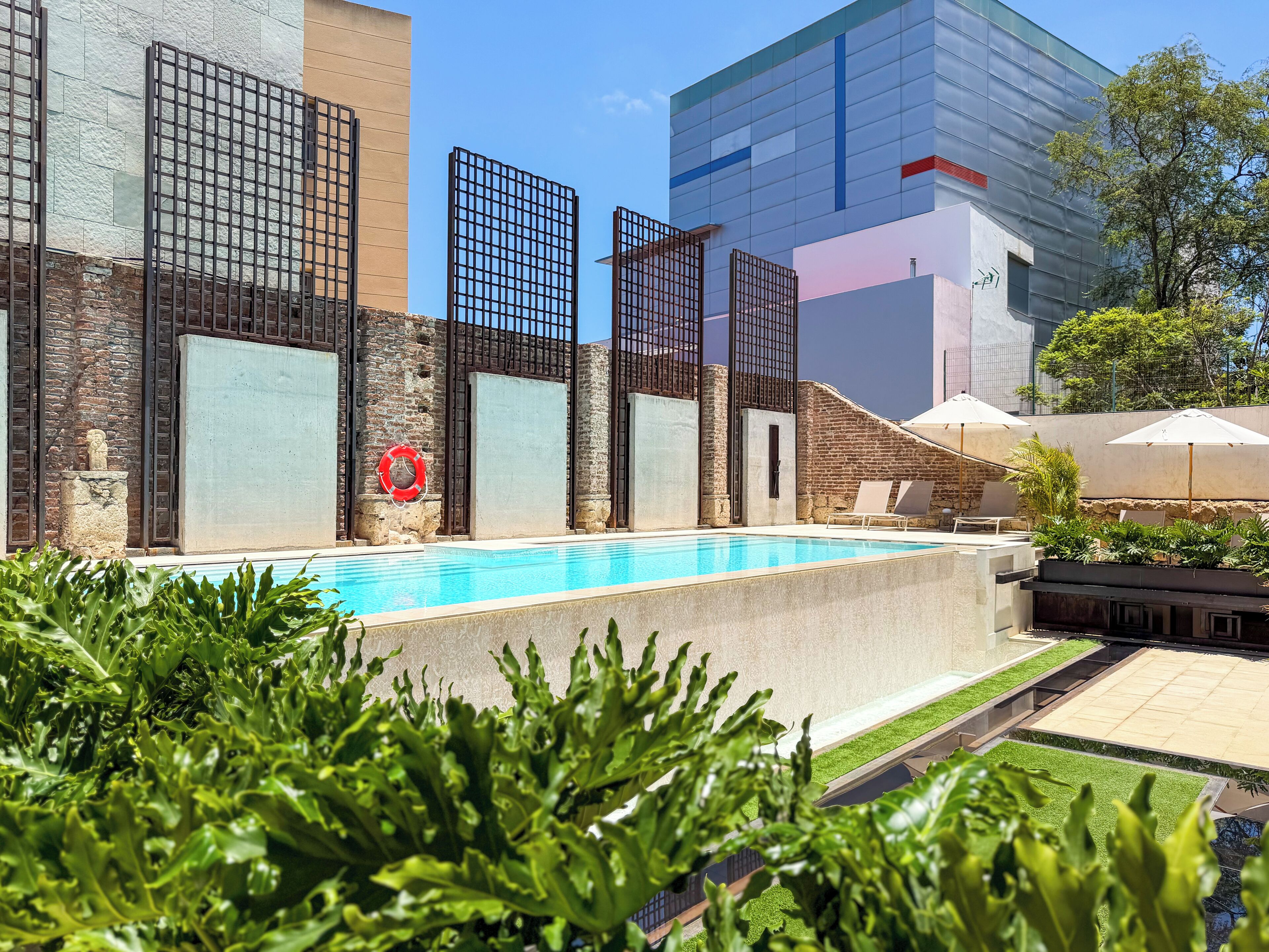 A swimming pool with a lifebuoy, a stone statue, and a brick wall.