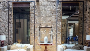 A modern interior with stone walls, two sofas, a central table with a vase, and a mirror.