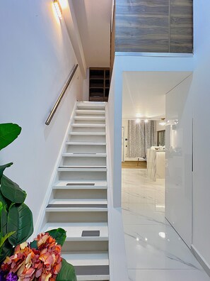 Ein modernes Interieur mit einer Treppe, die zu einem Raum mit Marmorboden und Blick ins Bad führt.