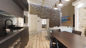 Una cocina moderna con una pared de piedra, un área de comedor con mesa de madera y una sala de estar con sofá.