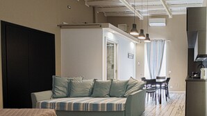 Una habitación con sofá, cama, mesa de comedor y zona de cocina.