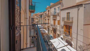 Una calle estrecha flanqueada por edificios, balcones y un cielo azul despejado.