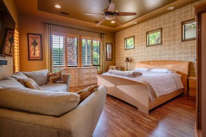 Ein Schlafzimmer mit Bett, einer Couch, einem Schreibtisch und einem Fenster mit Jalousien.
