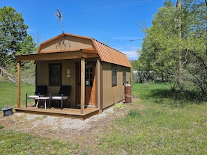 Eine kleine Holzhütte mit Veranda, zwei Stühlen, einem Tisch und einem Propangasbehälter.