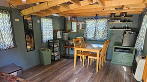Een kleine keuken met houten kastjes, een eettafel en een televisie.