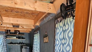 Een kleine keuken met een koelkast, een fornuis en een spoelbak. Er staat een houten eettafel met stoelen.