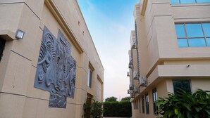 A building with a central corridor, large windows on the right, and a decorative relief on the left.