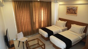 A hotel room with two beds, a television, a chair, and a small table.