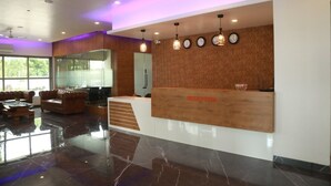 A reception area with a wooden reception desk, multiple clocks, and a seating area with sofas.