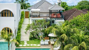 A two-story house with a swimming pool, a staircase leading to the upper level, and a garden with palm trees. - Villa Vista (Ubud)