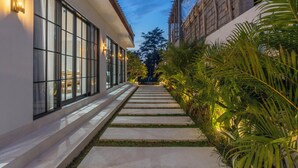 A pathway leading to a building with large windows and a well-lit exterior. - Villa Vista (Ubud)