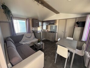 A compact living space with a sofa, a dining table, and a kitchenette. - 1 min 50 from the beach. 2-bedroom bungalow. (Camiers)