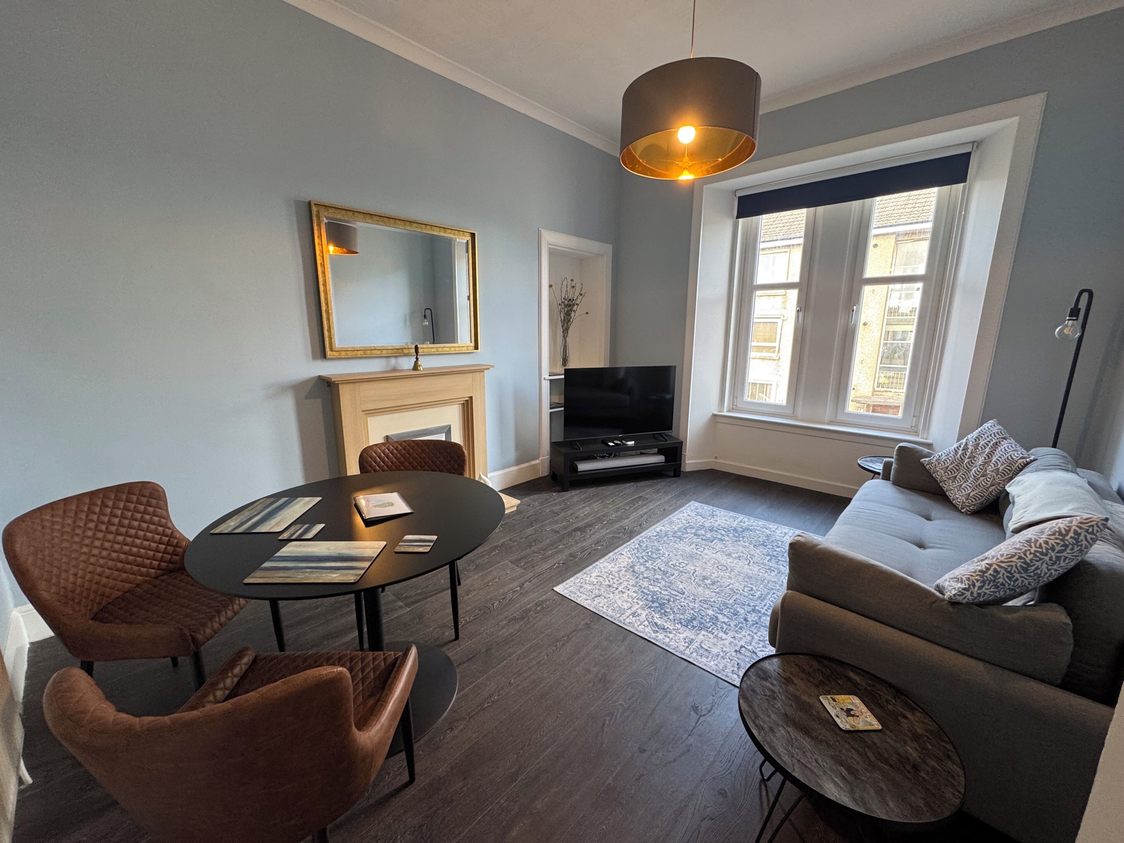 A modern living room with a fireplace, a television, a sofa, and a dining table.