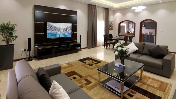 A modern living room with a flat-screen TV, sofas, a coffee table, and a dining area. - RURU TOWER (Manama)