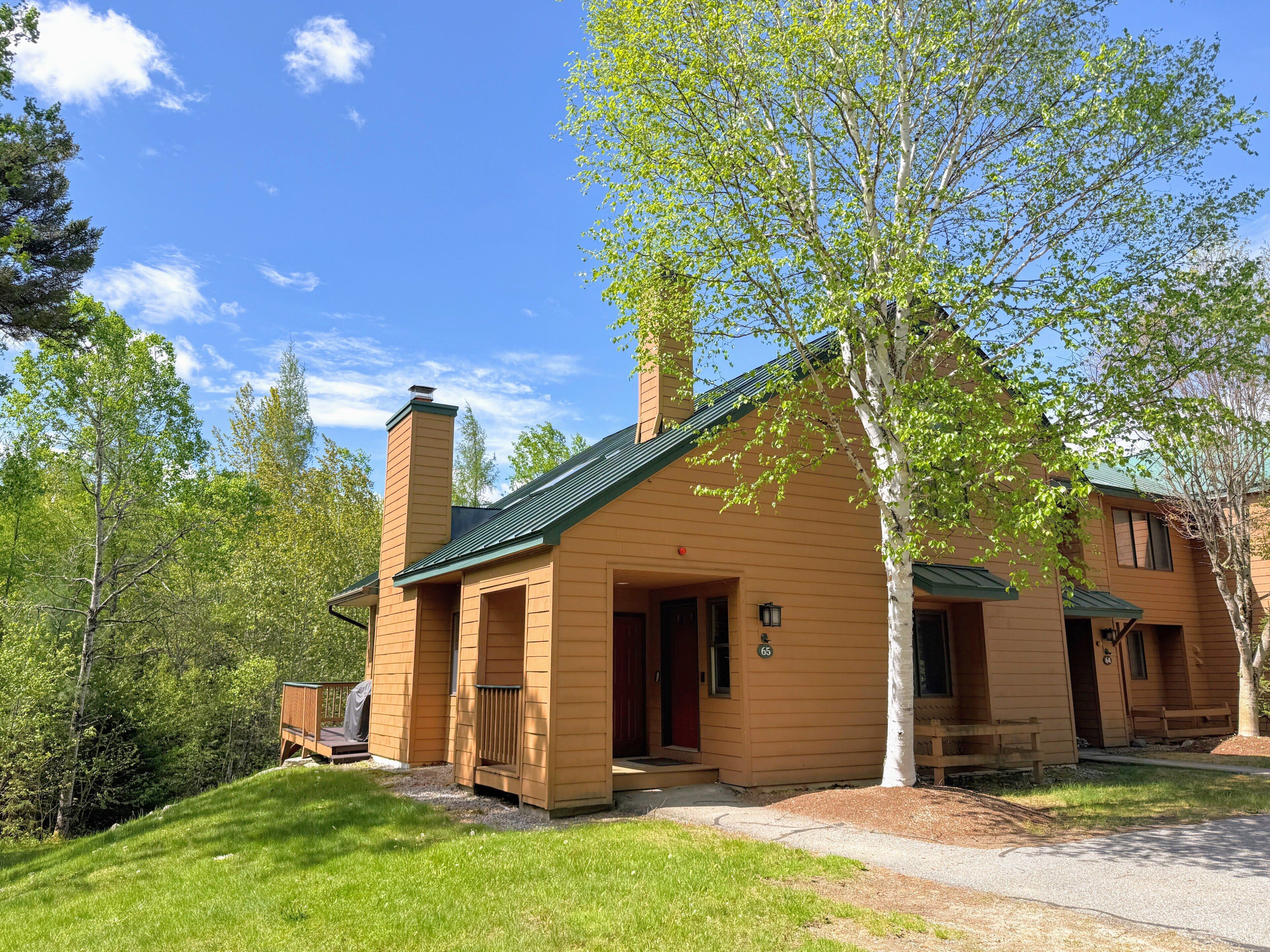 A lodge with a chimney, a porch, and a number 65 sign.
