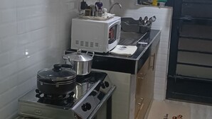 Kompakti keittiö, jossa on kaasuliesi, mikroaaltouuni ja puiset kaapit.