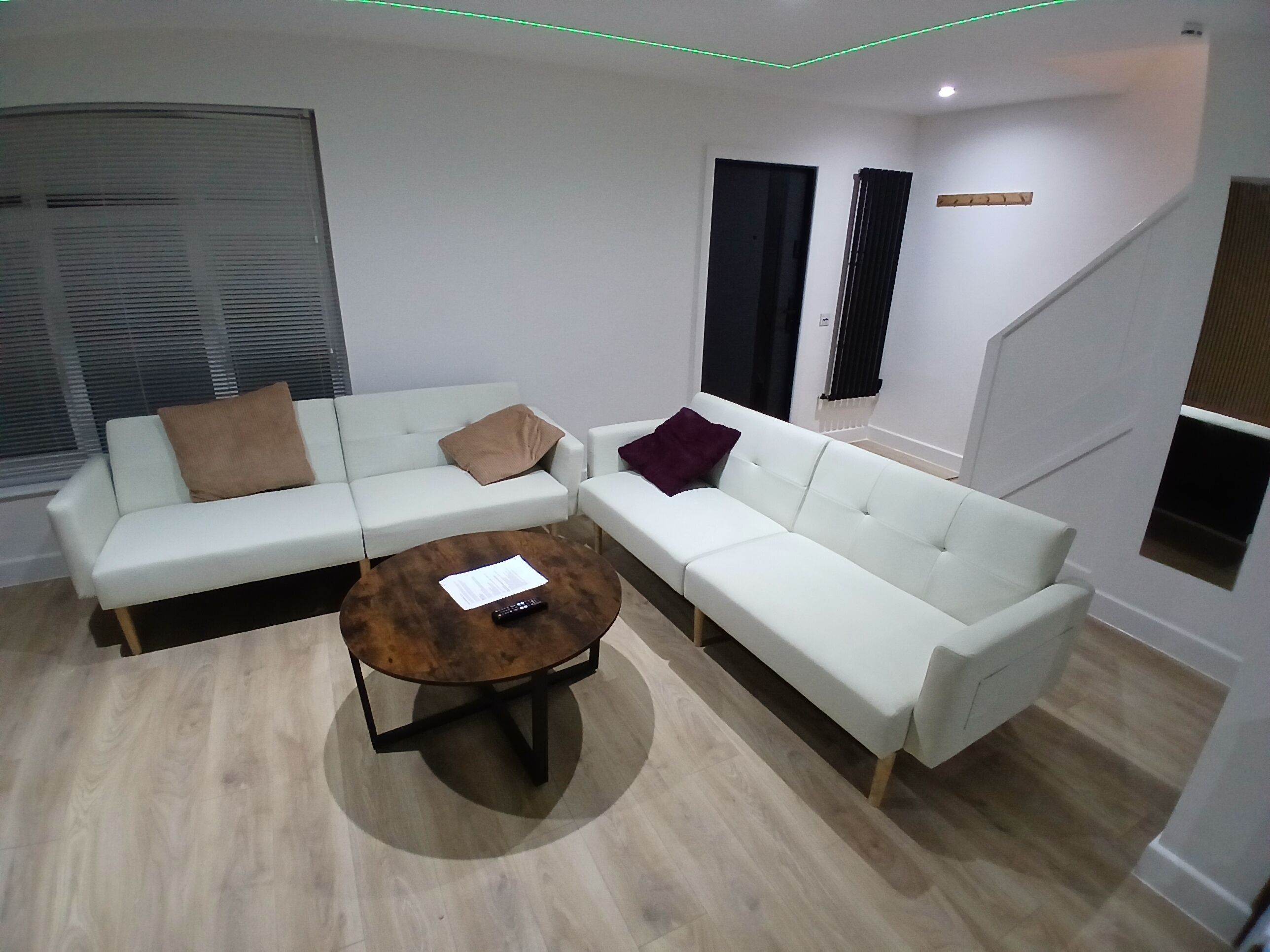 Un salon moderne avec un canapé blanc, une table basse ronde et un escalier.