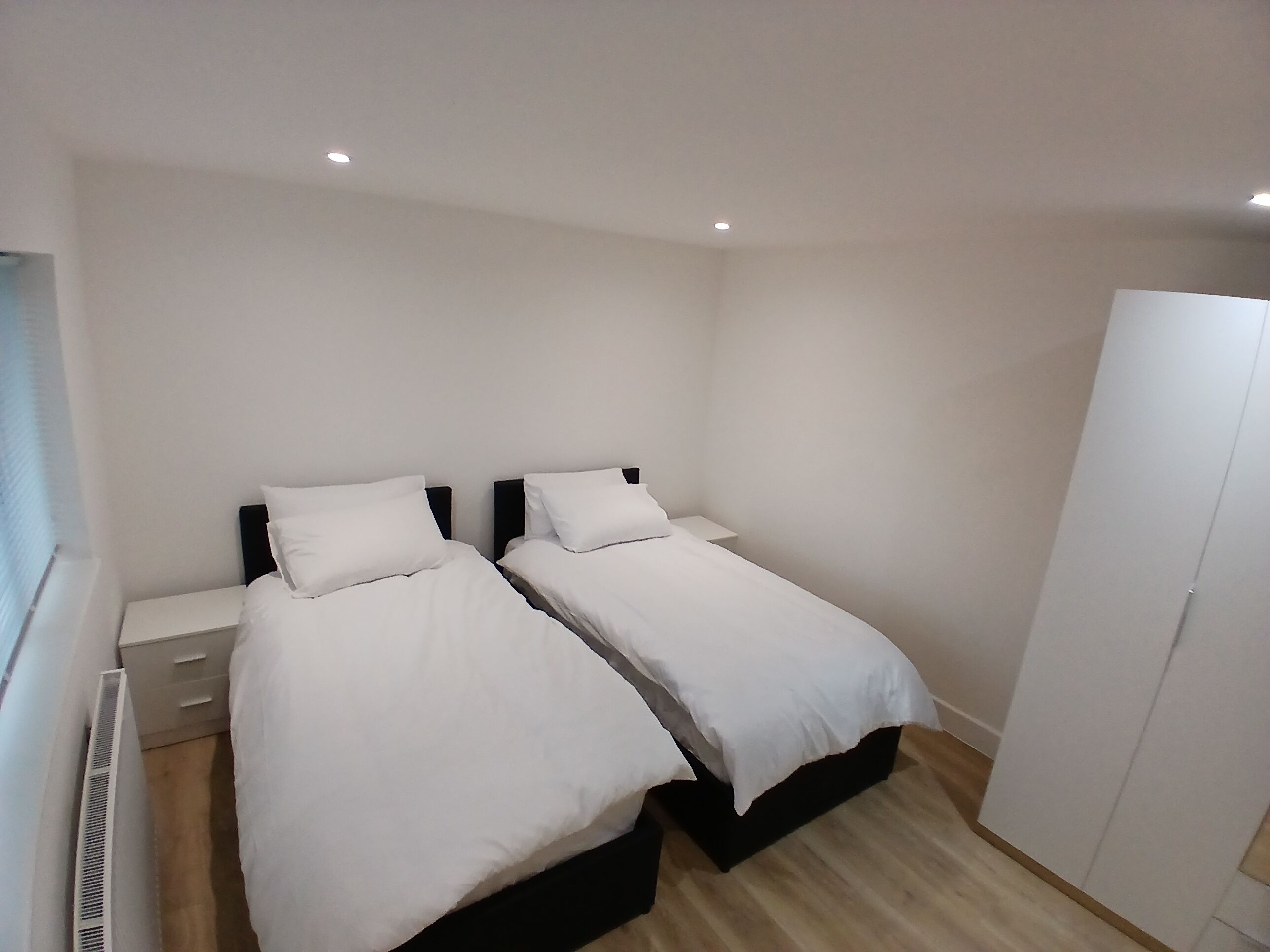 A bedroom with two beds, a wardrobe, and a radiator.