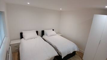 A bedroom with two beds, a wardrobe, and a radiator.