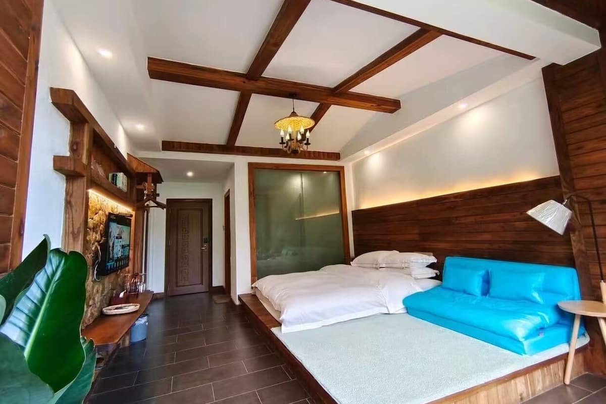 A bedroom with a bed, a blue sofa, a wooden ceiling, and a stone wall.