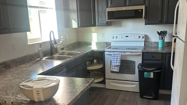 A kitchen with dark cabinets, a white stove, and a granite countertop. - Welcoming 4-bedroom house in Anchorage for a relaxing stay (Anchorage)