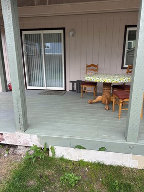 Une terrasse couverte avec une table et des chaises, une porte-fenêtre coulissante et un petit banc.