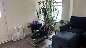 A living room with a stationary bike, a fan, a potted plant, and a couch. - Welcoming 4-bedroom house in Anchorage for a relaxing stay (Anchorage)