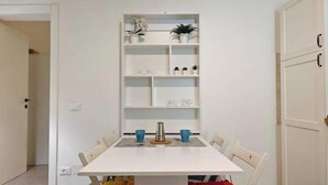 A dining area with a white table, blue cups, and a coffee pot. - Hostdomus - Oscar's House (Albenga)