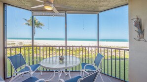 A covered outdoor area with a table and chairs, a ceiling fan, and a view of the beach. - RIVIERA CLUB BEACHFRONT RESORT CONDO w/ DIRECT GULF VIEWS! WRAP-AROUND LANAI! (Fort Myers Beach)