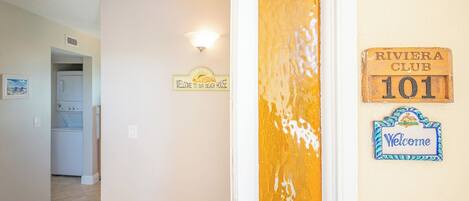 A hallway with a laundry room, a welcome sign, and a Riviera Club sign.
