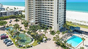 A high-rise hotel with a pool, beach view, and multiple parking spaces. - RIVIERA CLUB BEACHFRONT RESORT CONDO w/ DIRECT GULF VIEWS! WRAP-AROUND LANAI! (Fort Myers Beach)