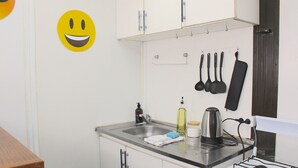 Ett kök med en diskho, en spis och köksredskap som hänger på väggen.