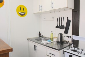 Una cocina con un fregadero, estufa y utensilios colgados en la pared.