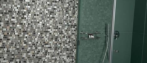 A modern bathroom with a mosaic tile wall, a glass-enclosed shower, and a white bathtub with a built-in seat.