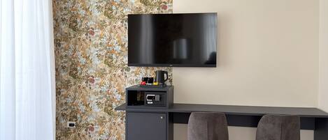 A modern living room with a sofa, a TV mounted on the wall, a small cabinet, and two chairs.