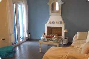 Ein Zimmer mit Kamin, Bett, Glastisch und Blick durch ein Fenster.