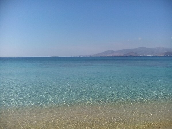 Ein freier Blick auf einen Strand mit ruhigem Wasser und entfernten Bergen.