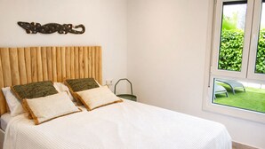 Een slaapkamer met een houten hoofdbord, een witte spreideken en twee kussens.