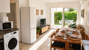 Een moderne keuken met een wasmachine, een koelkast, een magnetron en een eethoek met een tafel voor vier personen.