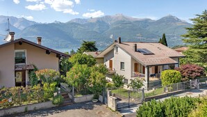 Un quartier résidentiel avec des maisons, un jardin et une chaîne de montagnes en arrière-plan.