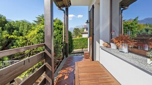 Un balcon doté d’un plancher en bois, d’une rambarde en métal et offrant une vue sur une chaîne de montagnes.