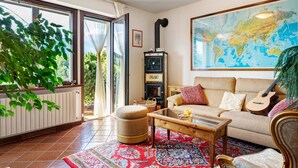 Un salon avec un canapé, une table basse, une guitare, une carte accrochée au mur et un radiateur.