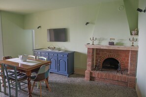 Ein Essbereich mit Holztisch, Stühlen, einem blauen Schrank und einem Kamin aus Backsteinen mit Dekorationen.