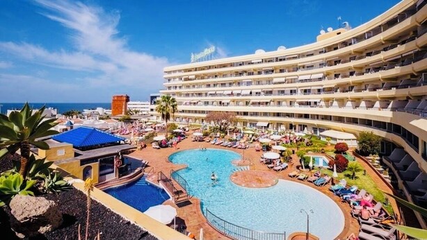 Ein Hotel mit großzügigem Poolbereich, mehreren Balkonen und Meerblick.