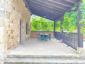 A stone building with a covered patio area, featuring a table and chairs. - Charming Rural Retreat with Garden — Countryside & near the Coast for up to 6 (Reocín)
