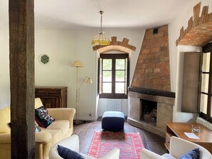 A living room with a fireplace, a sofa, a coffee table, and a lamp. - Charming Rural Retreat with Garden — Countryside & near the Coast for up to 6 (Reocín)