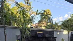 A modern building with a stone facade, a water feature, and lush greenery. - Urban stays (Nairobi)